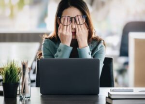 Woman at work rubbing eyes looking distressed