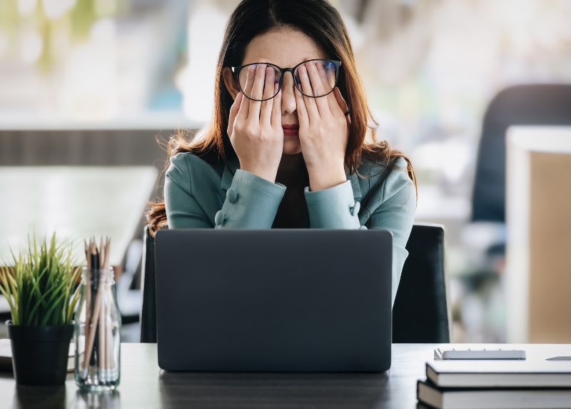 Woman at work rubbing eyes looking distressed
