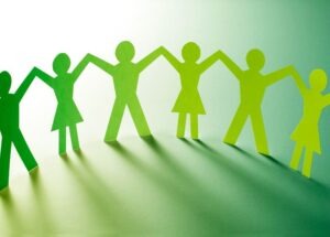 Green paper cut-out figures holding hands in a row, symbolizing unity, teamwork, and connection