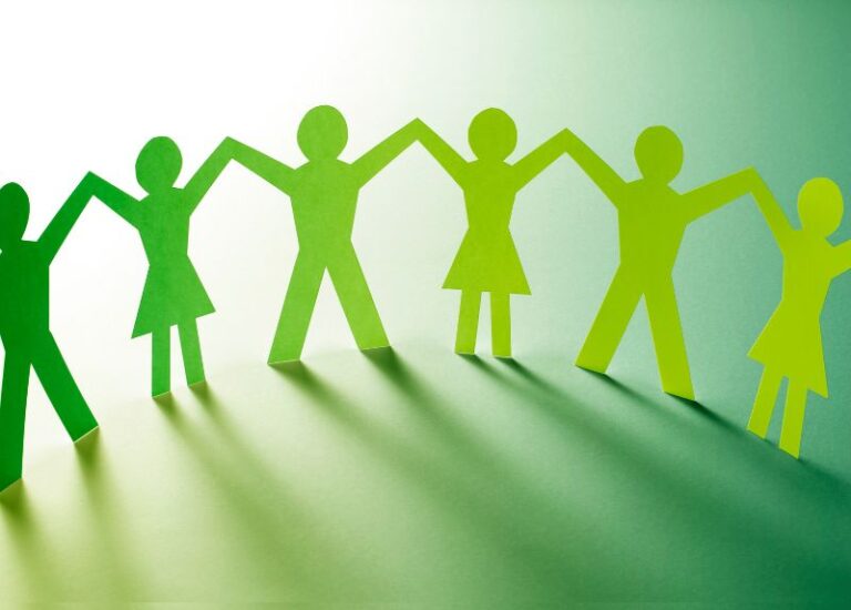 Green paper cut-out figures holding hands in a row, symbolizing unity, teamwork, and connection