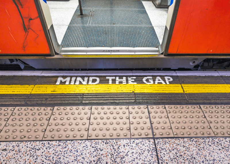 London Underground platform with 'Mind the Gap' warning, representing the gap between employee experience initiatives and everyday work.