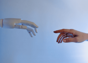 Human hand reaching toward a robotic hand, symbolising collaboration between people and AI.