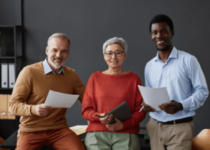 Diverse group of colleagues of different ages and backgrounds holding documents and a tablet, representing experience and inclusion in the workplace.